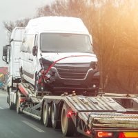 Flatbed truck hauling damaged work van