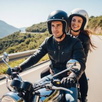 Adventure awaits: a couple riding a motorcycle on a scenic mountain road on a sunny day.