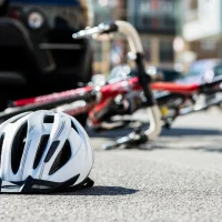 white-helmet-on-the-ground-in-front-of-a-fallen-bicycle-and-a-parked-car