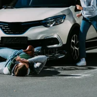 a-cyclist-is-lying-in-front-of-a-white-car-on-a-street