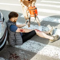 injured-man-sits-on-crosswalk-beside-car