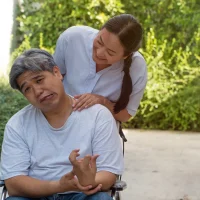 a-man-in-a-wheelchair-makes-a-humorous-face-while-a-woman-stands-behind-him